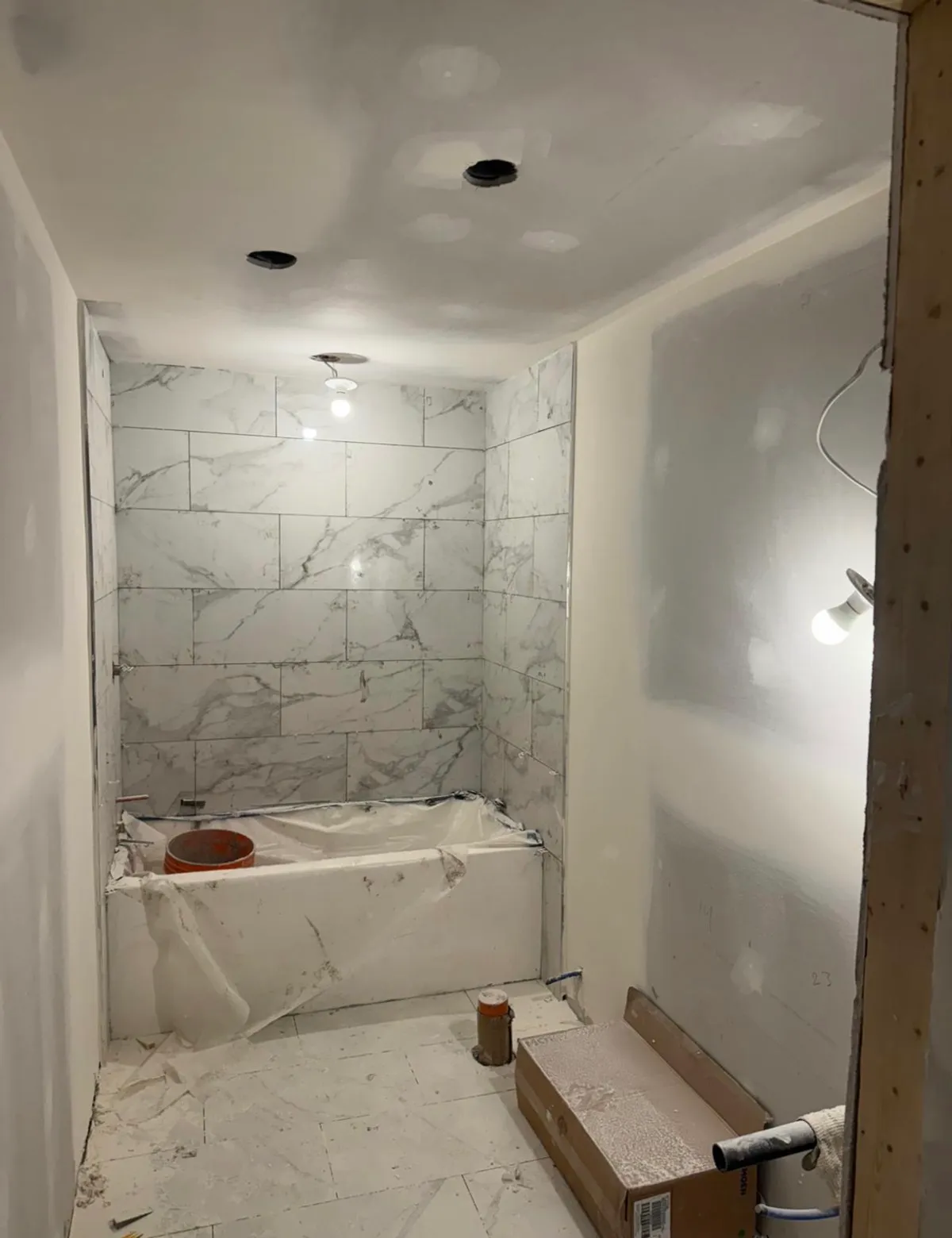 Bathroom mid-construction with marble tile being installed