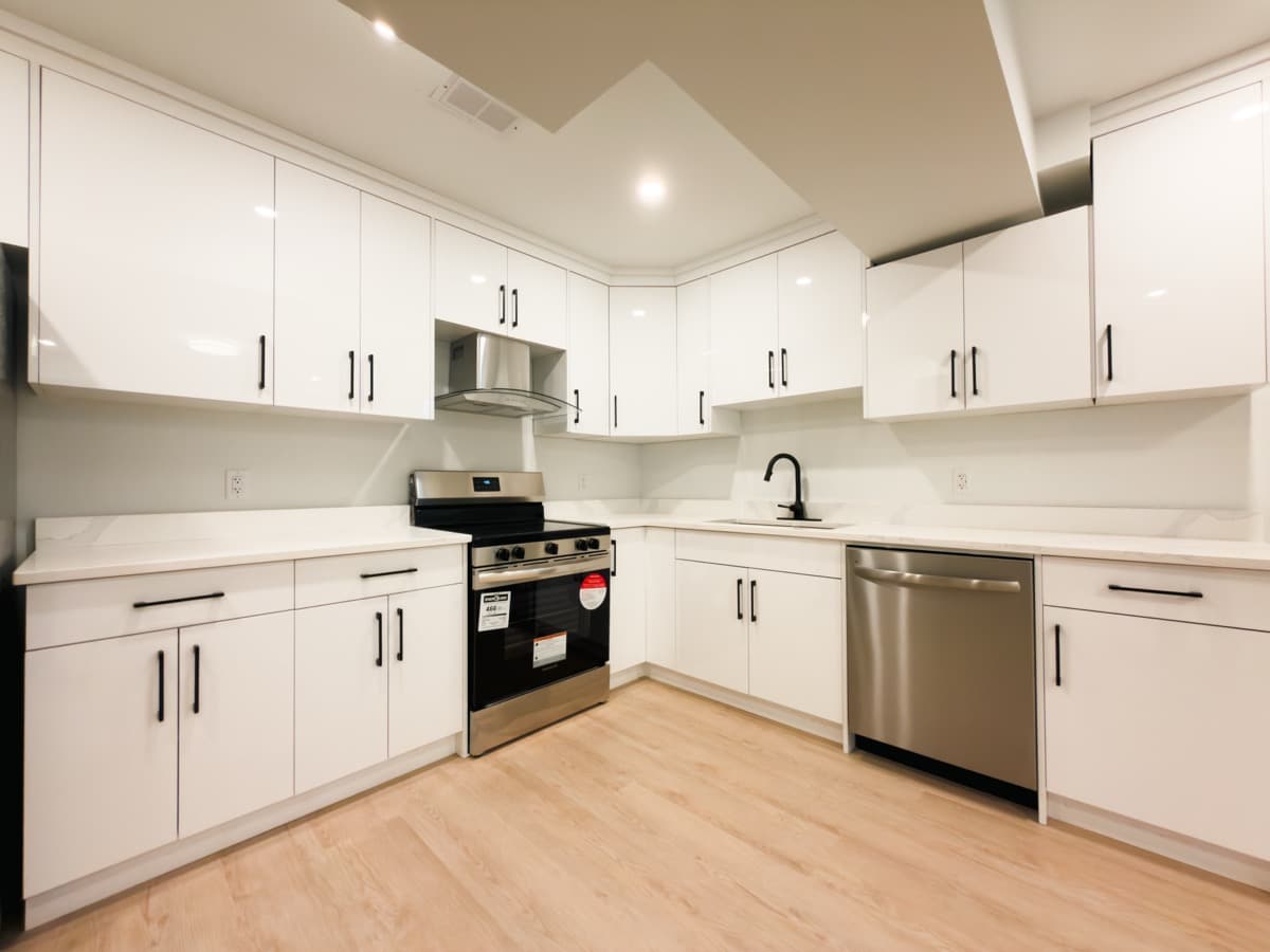Completed basement suite kitchen with white cabinets and stainless steel appliances