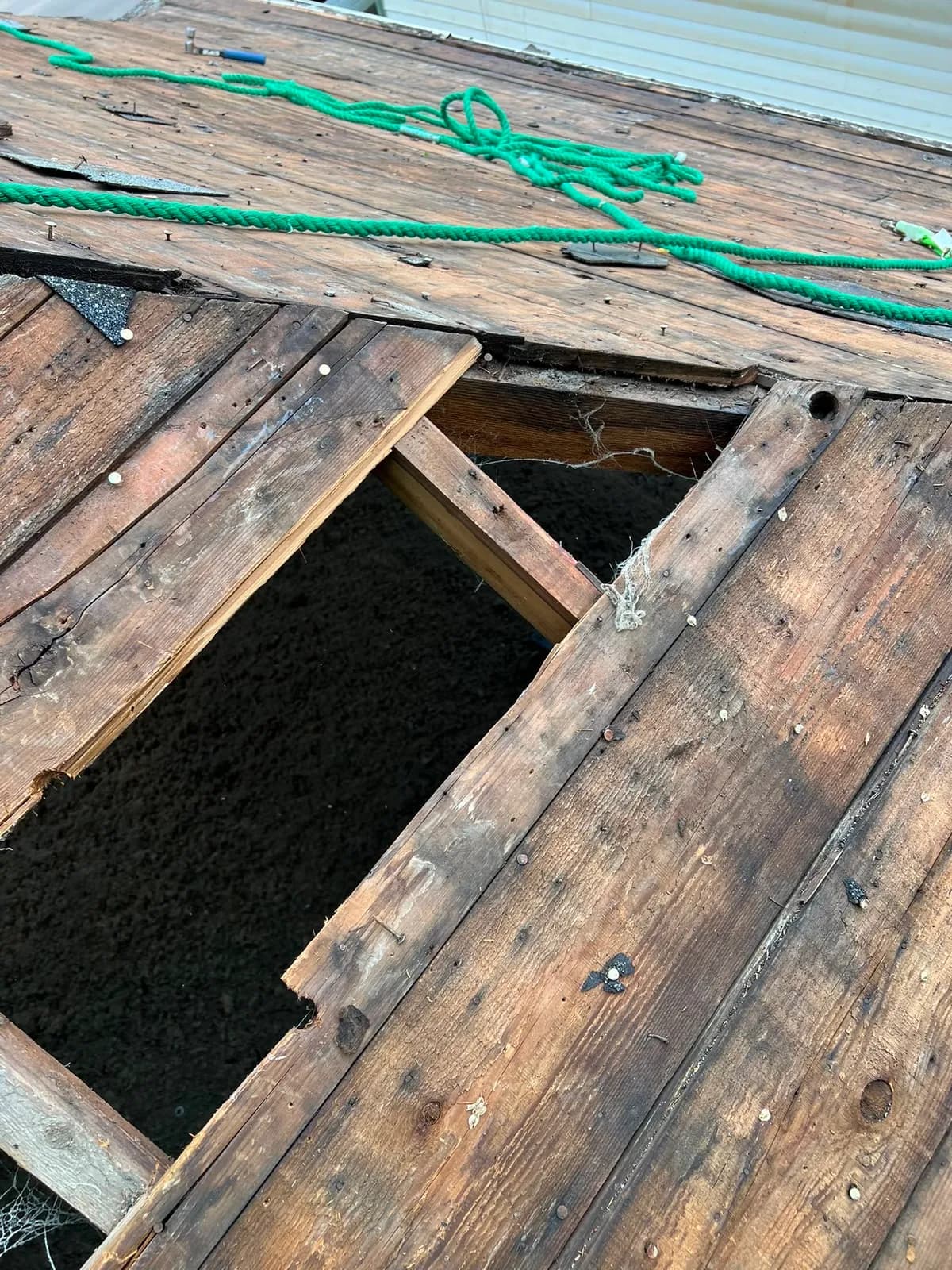 Damaged roof sheathing with holes exposed during restoration tear-off
