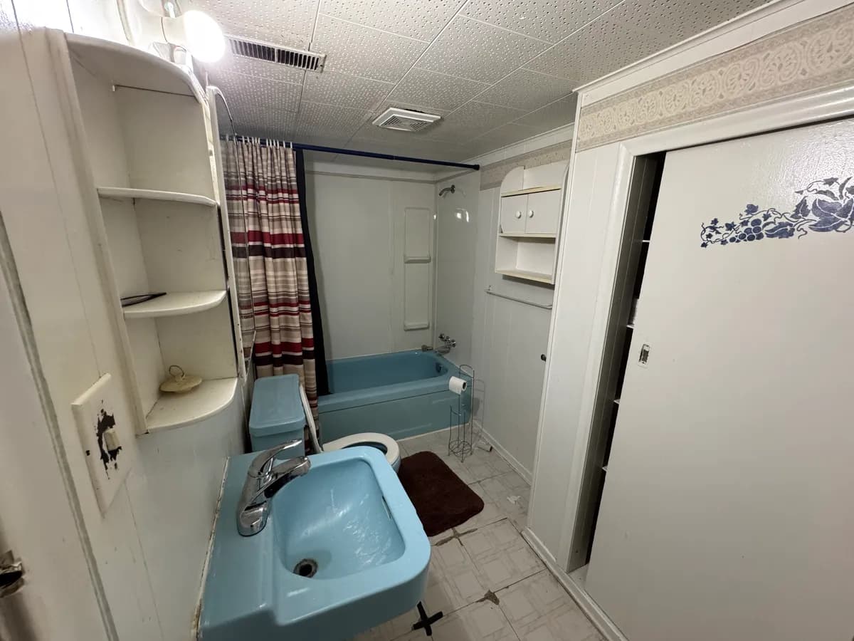 Dated bathroom with 1970s blue fixtures and worn finishes before renovation