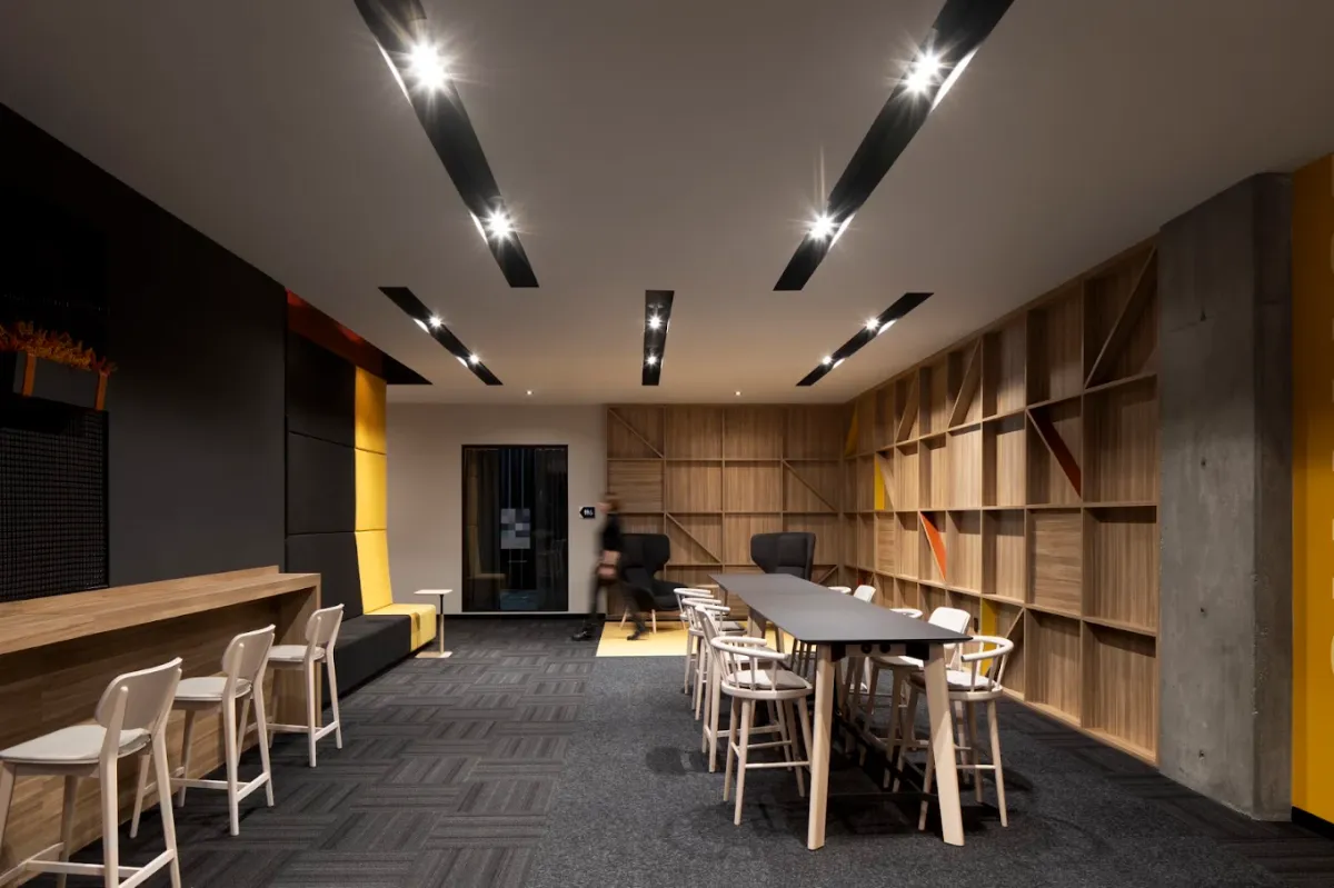 Finished lounge at Alt Hotel Saskatoon with angled black ceiling baffles and built-in wood cubby shelving