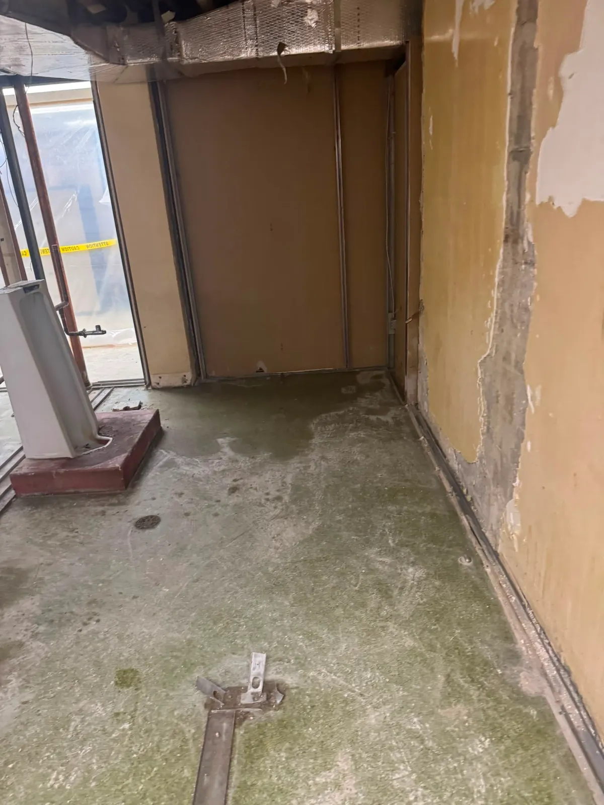 Gutted commercial room mid-demolition with exposed studs and old vinyl subfloor