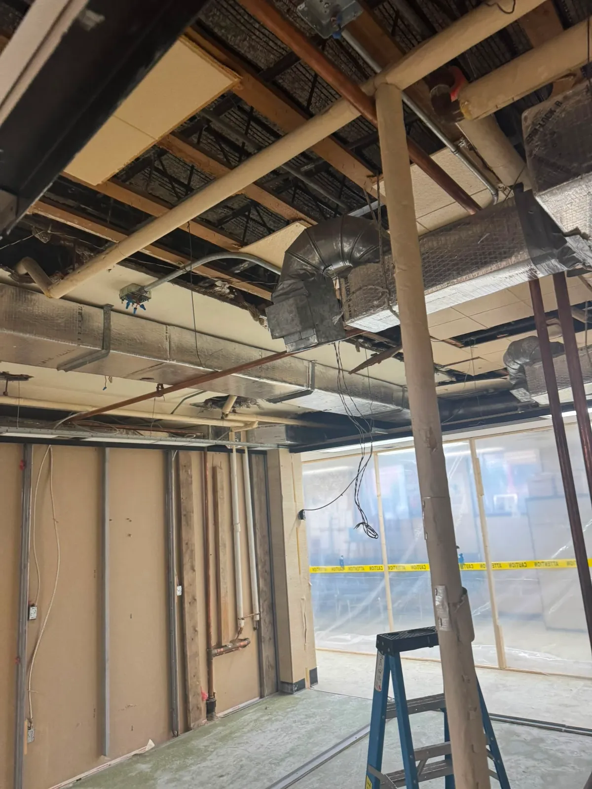 Exposed ceiling ductwork and structural beam in a gutted commercial room