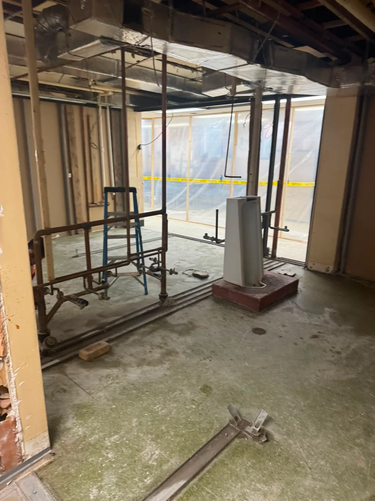 Gutted commercial room with a pipe cart and exposed brick corner