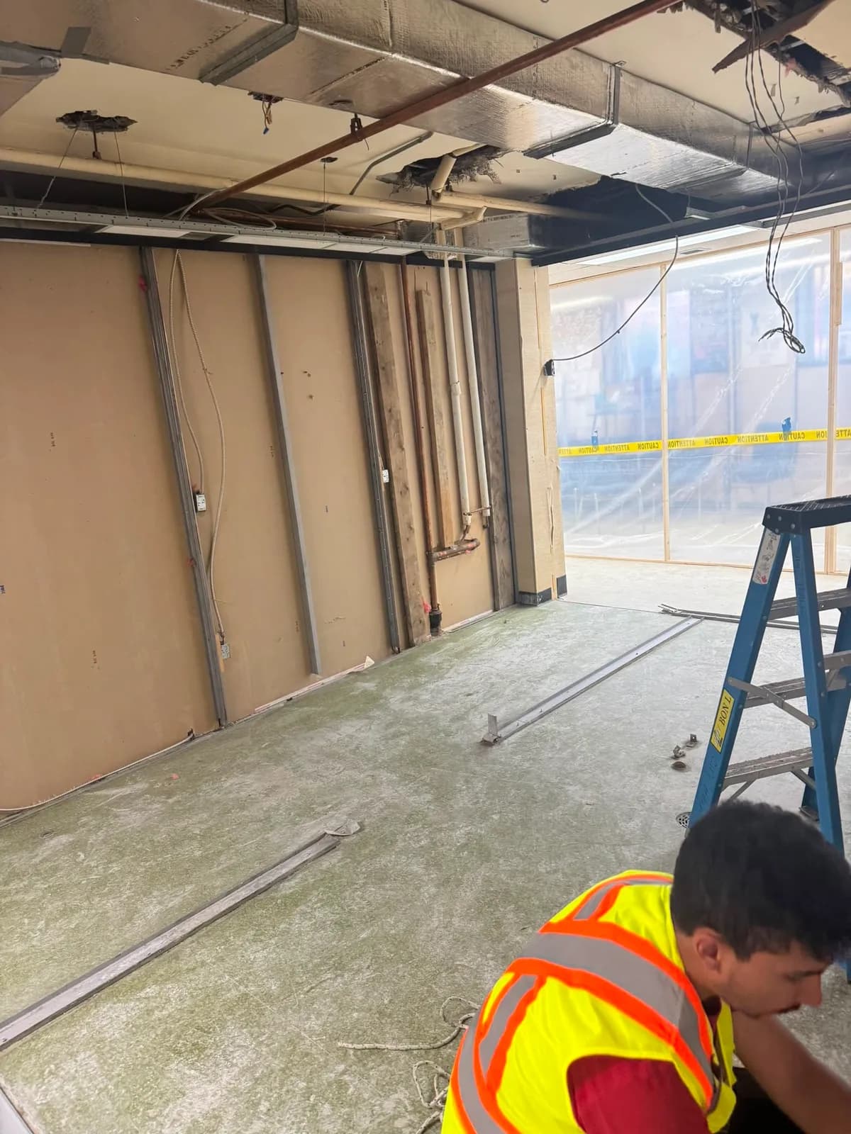 Open commercial space gutted to the ceiling deck with a worker present