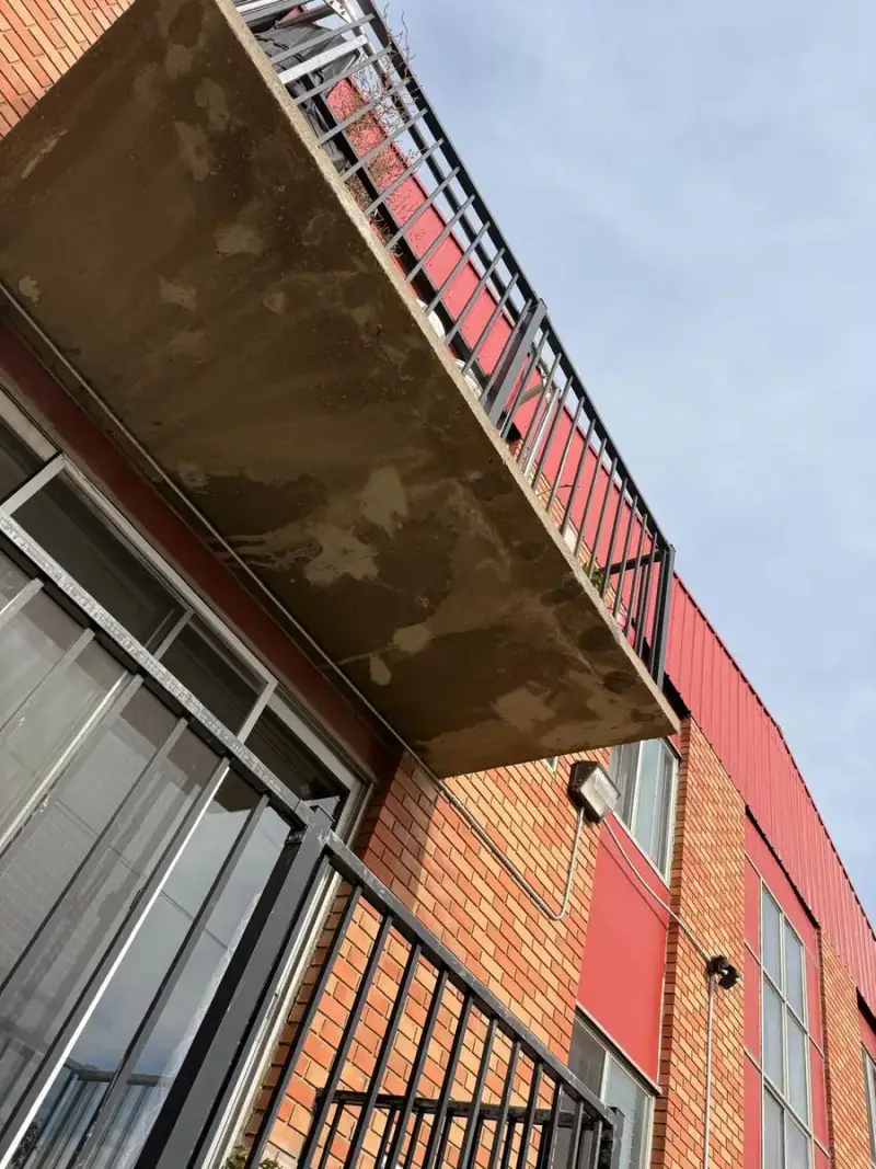 Concrete balcony slab underside showing water staining and surface loss