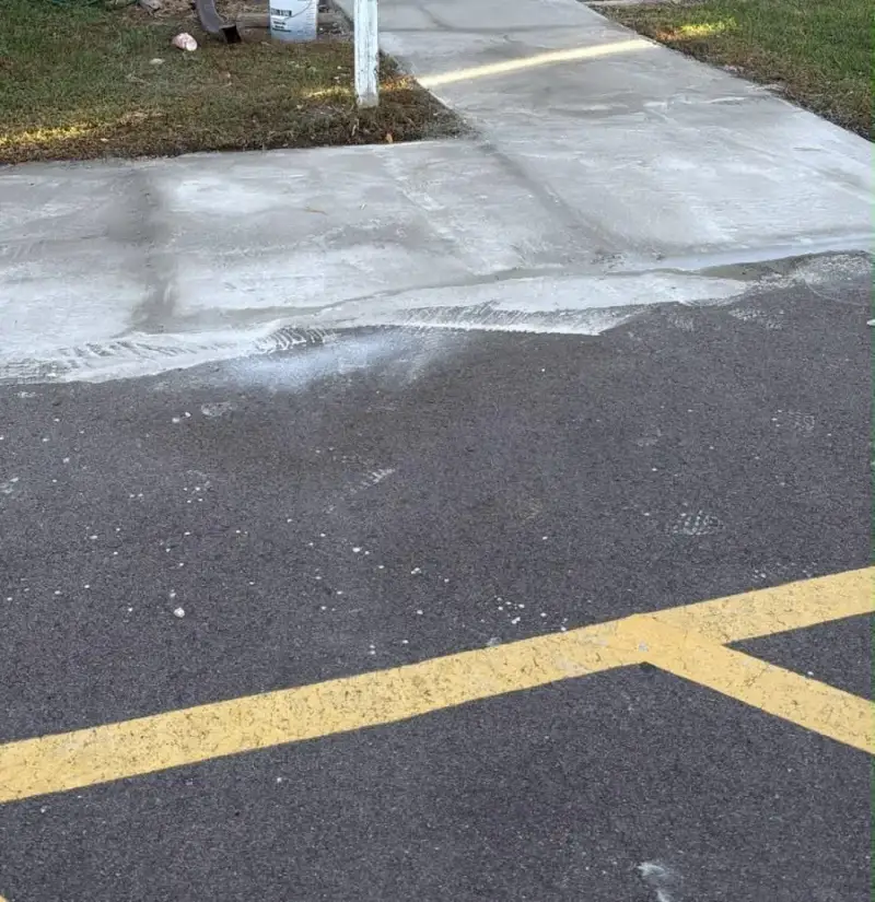 New concrete apron meeting the asphalt parking lot at an apartment entrance
