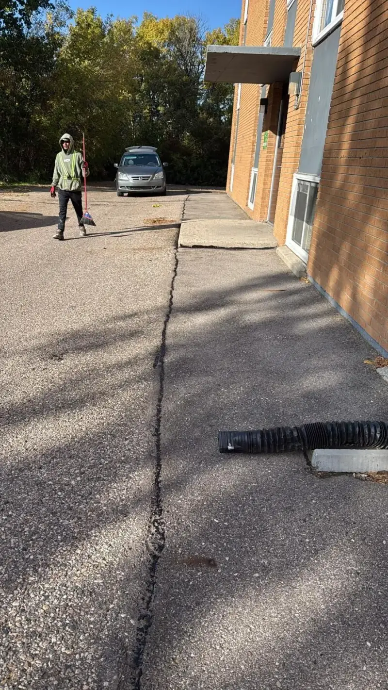 Meadow crew member sealing cracks along an apartment parking lot in Saskatoon