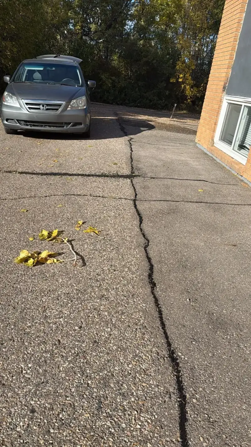Network of sealed cracks across an apartment building parking lot