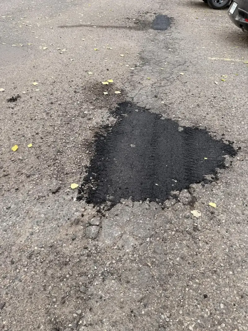Pothole patched with hot-mix asphalt in a rental building parking lot