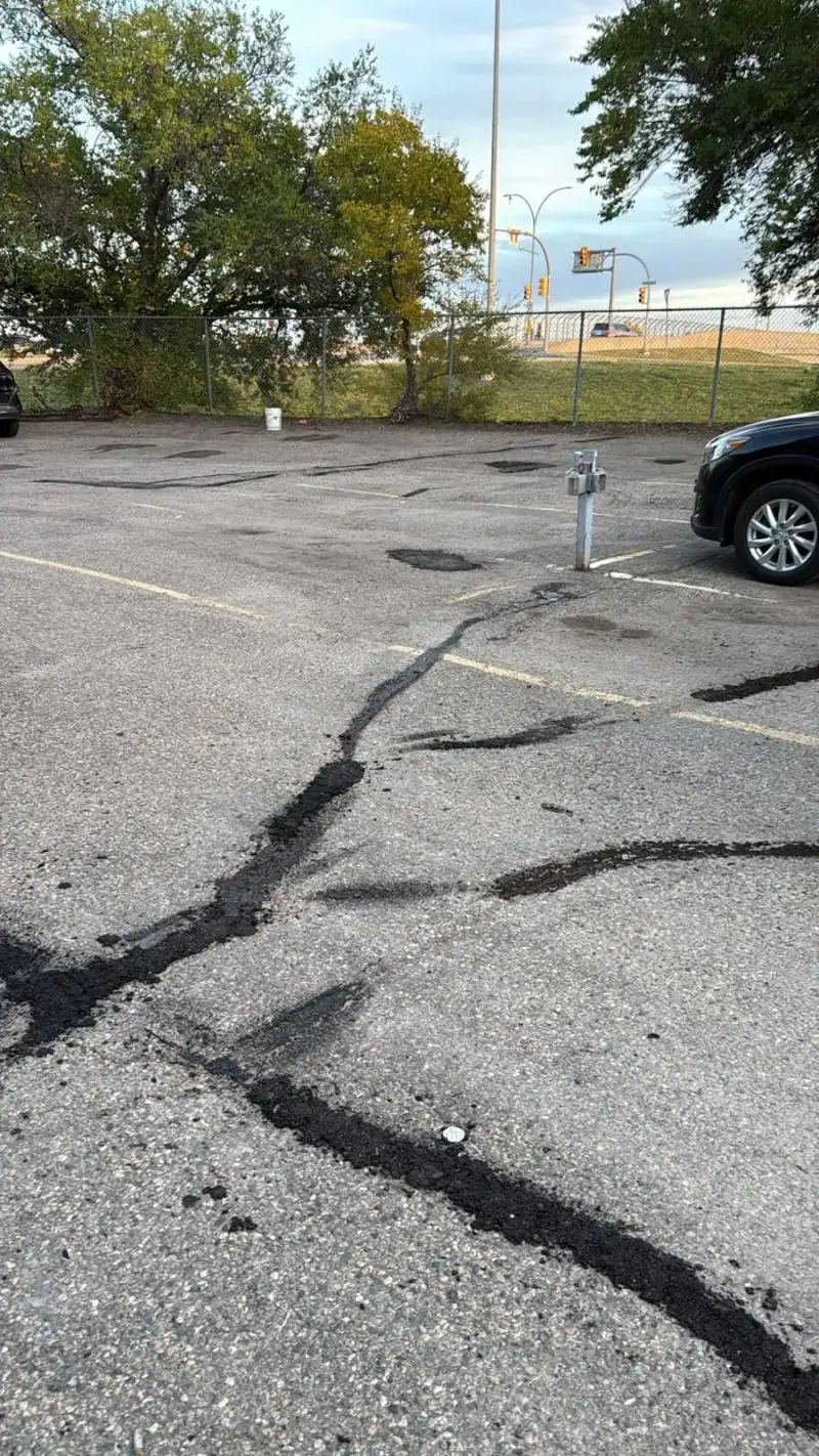 Wide view of a Saskatoon apartment parking lot with sealed cracks and patches